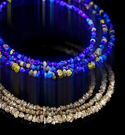 Necklace of rough light brown diamonds under UV light (top) and normal light (bottom)