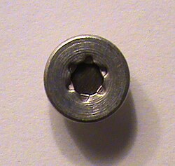 Americium-241 capsule as found in smoke detector. The circle of darker metal in the center is americium-241; the surrounding casing is aluminium.