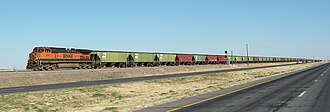 BNSF Dash 9-44CW #1041 leading a manifest freight train northwest of Shallowater, Texas, running on former ATSF railroad tracks that run parallel to U.S. Route 84 as they cross the high plains of the Llano Estacado. Immediately behind the locomotive are cars painted in the old Burlington Northern livery.