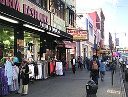 Spanish signs advertising "La Casa de las Novias", "Cuchifritos" and Banco Popular are visible in a row of stores in this photo of El Barrio at Lexington and 116th in Manhattan, New York, U.S.