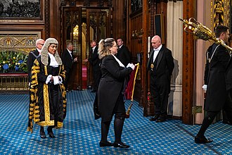 The Lord High Chancellor (Shabana Mahmood) wearing full ceremonial dress at the 2024 State Opening of Parliament, preceded by her purse-bearer and a serjeant-at-arms.