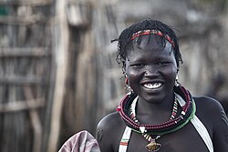 A young South Sudanese girl smiling in traditional attire