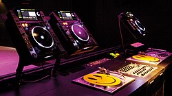 DJ booth in a nightclub, consisting of three CDJs (top), three turntables for vinyl records and a DJ mixer