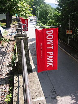 Towel Day Innsbruck − Towels with a silkscreen print as homage to Douglas Adams. Next to the words 'DON'T PANIC' there are the GPS data from the city Innsbruck where Adams had the idea for the Hitchhiker's Guide to the Galaxy.[26]