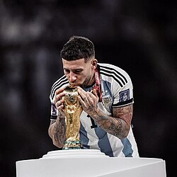 Otamendi kissing the FIFA World Cup Trophy after winning with Argentina in 2022.