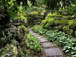 The Rock Garden in Sonnenberg Gardens, New York, shaded by trees, makes use of shade-plants and moss, creating a variety of foliage textures and shades of green.