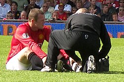 Rooney being treated for a broken foot during a Premier League match against Reading in August 2007