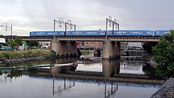 An electric commuter rail train crossing a bridge over the Matanza River