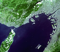 Satellite photo of Kansai Airport (lower-right island) in Osaka Bay. Kobe Airport is being built on the unfinished island near the middle of the photo. Central Osaka is in the upper-right corner, along with Osaka International.