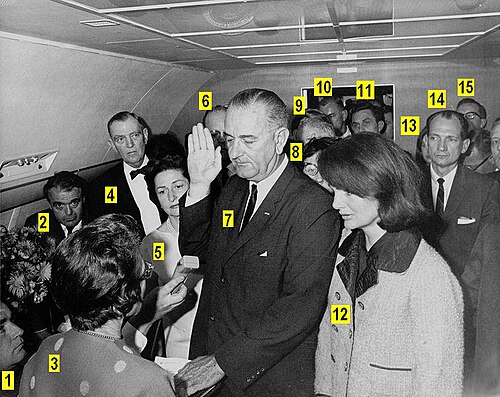 Lyndon B. Johnson taking the oath of office on Air Force One following the assassination of John F. Kennedy, Dallas, Texas. Identified persons include: (#1) Malcolm Kilduff (press secretary), (#2) Jack Valenti (media adviser), (#3) Judge Sarah T. Hughes, (#4) Congressman Albert Thomas, (#5) Lady Bird Johnson, (#6) Chief Jesse Curry (Dallas police chief), (#7) Lyndon B. Johnson, (#8) Evelyn Lincoln (personal secretary to John F. Kennedy), (#9) Congressman Homer Thornberry, (#10) Roy Kellerman (USSS agent), (#11) Lem Johns (USSS agent), (#12) Jacqueline Kennedy, (#13) Pamela Turnure (press secretary to Jacqueline Kennedy), (#14) Congressman Jack Brooks, (#15) Bill Moyers (Peace Corps deputy director). Photo by Cecil W. Stoughton.
