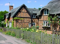 Vernacular thatched cottages (built in 1812–1816) in Woburn Street, Ampthill, Bedfordshire, surrounded by garden.