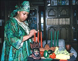 A woman lighting candles for Kwanzaa. The black candle in the middle represents unity, the three green candles on the right represent earth, and the three red candles on the left represent the struggle of African Americans or the shedding of blood.[20]