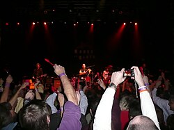 Cowboy Mouth performing "Everybody Loves Jill" on Mardi Gras night in Houston, 2010, with fans waving red spoons in anticipation of their cue to throw them at the band.