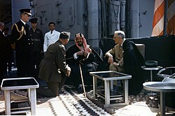 Ibn Saud converses with U.S. president Franklin D. Roosevelt (right) in 1945 through interpreter William A. Eddy, on board the USS Quincy, after the Yalta Conference. Fleet Admiral William D. Leahy (left) watches.