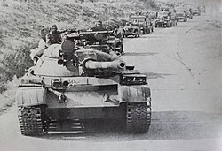 Column of Syrian tanks and trucks headed by a T-55 tank