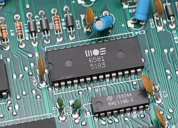Through-hole devices mounted on the circuit board of a mid-1980s home computer. Axial-lead devices are at upper left, while blue radial-lead capacitors are at upper right.