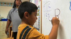 Oklahoma Cherokee language immersion school student writing in the Cherokee syllabary