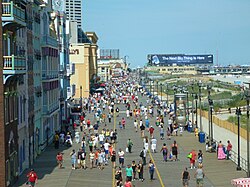 People walking along a wide pathway near the ocean on a sunny day