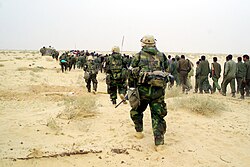 US Marines escort captured enemy prisoners to a holding area in the desert of Iraq on 21 March 2003