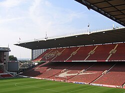 A grandstand at a sports stadium. The seats are predominantly red.