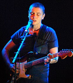 Sinéad O'Connor playing a Fender guitar with a capo