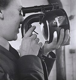An air traffic controller using a handheld Aldis lamp to signal a plane to land.