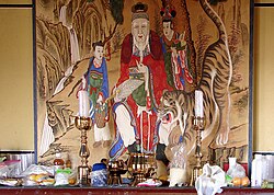 A shrine with a depiction of a mountain spirit, offerings and candles