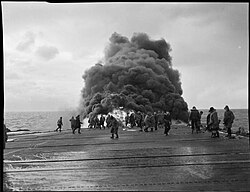 Black smoke rises after a Grumman Avenger crashes on the flight deck of Tracker whilst on Russian convoy duty