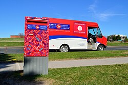 A Canada Post delivery truck and mailbox. The truck features a side panel ad that spotlights the postal service's role in delivering e-commerce goods.
