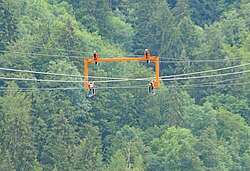 The returning haul cable (top), the support cables (middle), and the non-returning haul cable (bottom) are visible here. These structures appear at regular intervals along the line, to hold the cables together and keep a consistent track width