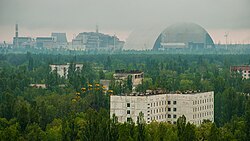 The town of Pripyat abandoned since 1986, with the Chernobyl plant and the Chernobyl New Safe Confinement arch in the distance