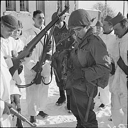 Men from the 5th Battalion, Queen's Own Cameron Highlanders wearing snow suits, inspect the weapons of two GIs from the U.S. 87th Division during the link-up of the two Allied armies at Champlin in Belgium, 14 January 1945.