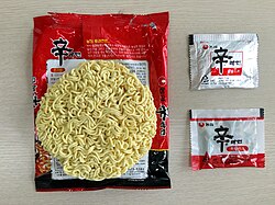 A packet of Shin Ramyun. The Chinese character 辛, meaning 'spicy', is prominently displayed.