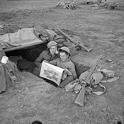 Men of the 2nd Royal Inniskilling Fusiliers reading Ireland's Saturday Night in their foxhole in the Anzio bridgehead, 17 March 1944