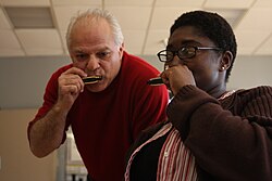A music therapist from a "Blues in the Schools" program plays harmonica with a US Navy sailor at a Naval Therapy Center.