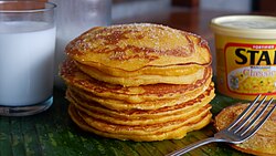 Filipino pancake, also known as hotcake, is typically yellow in color and is a popular street food served with margarine and sugar.