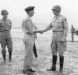 General Sir Bernard Montgomery shakes hands with Lieutenant General George S. Patton at an airport at Palermo, Sicily, 28 July 1943. Major General Geoffrey Keyes, deputy commander of Patton's Seventh Army, stands to the far left of the picture.