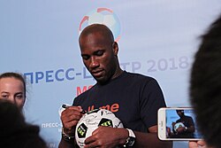 Drogba signing a football at a press conference in Moscow, July 2018