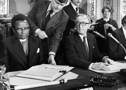 Bishop Abel Muzorewa signs the Lancaster House Agreement, seated next to British Foreign and Commonwealth Secretary Lord Carrington.