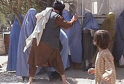 A member of the Taliban's religious police beating an Afghan woman in Kabul on 26 August 2001