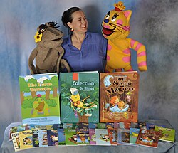 Veronica Bonilla with printed books, 2014, with July the Frog and Renata the Cat, characters from two of hers books.
