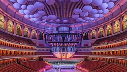 Acoustic diffusing discs (lit in purple/blue) hanging from the roof of the hall. The fluted aluminium panels are seen behind.