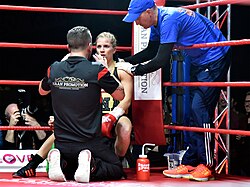 Boxer Tina Rupprecht receiving instructions from her trainer while being treated by her cutman in the ring corner between rounds
