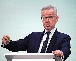 Gove gesturing with his right hand behind a lectern