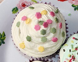 A frosted muffin garnished with confetti candy