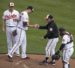 A pitcher handing off the ball after being taken out of the game during a mound meeting.