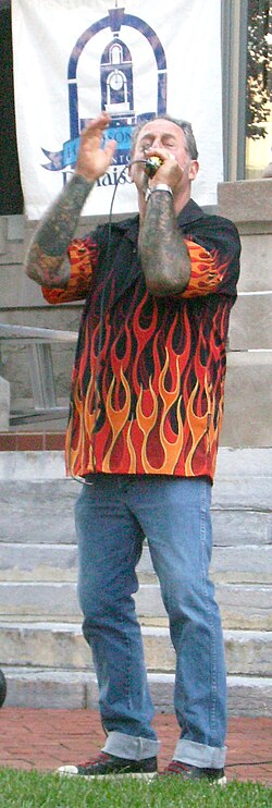 Mark Wenner cups his hands around a "bullet mic" as he plays an amplified harmonica.