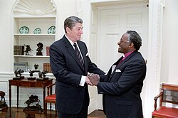 US President Ronald Reagan meeting with Desmond Tutu in 1984. Tutu described Reagan's administration as "an unmitigated disaster for us blacks",[162] and Reagan himself as "a racist pure and simple".[163]