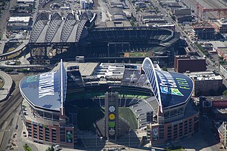 Two stadiums in an industrial area. Both have roofs with large arched trusses.