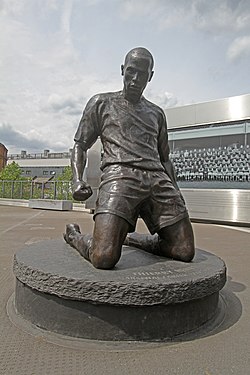 Henry statue outside Arsenal's Emirates Stadium. The statue recreates Henry's goal celebration where he slid to his knees after a goal against Spurs in 2002.[166]